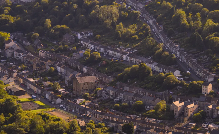 Rows of terraced houses climbing a green valley hillside, the kind of colliery-era housing common in Betws