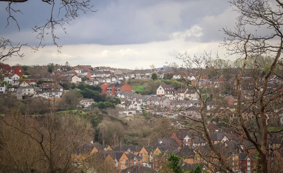 A mixed-era UK residential suburb seen from a hillside, older and newer housing side by side, the kind of mix common in Cross Hands